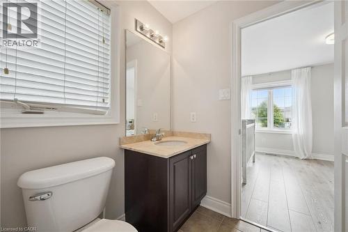 Bathroom featuring a dark wood-finish vanity, light-toned countertop, and a vanity mirror with a three-light fixture - 517 Topper Woods Crescent, Kitchener, ON 