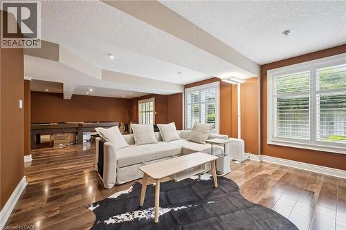 Spacious open-concept room featuring warm-toned walls, recessed lighting, and wood-finish flooring - 517 Topper Woods Crescent, Kitchener, ON 