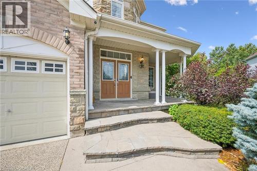 Stone exterior with brick accents, covered front porch, double entry doors with decorative glass, and a paved stone walkway - 517 Topper Woods Crescent, Kitchener, ON 