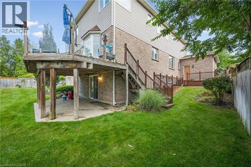 Expansive backyard featuring a multi-level wood deck with glass railing, a lower-level concrete patio, and mature landscaping - 517 Topper Woods Crescent, Kitchener, ON 