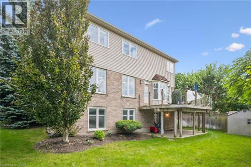 Expansive rear yard featuring a wooden deck with glass railing, a bay window, and a storage shed - 517 Topper Woods Crescent, Kitchener, ON 