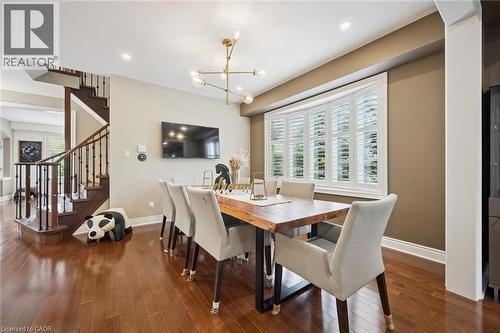 Rich wood-finish flooring, a contemporary chandelier, and a bay window with plantation shutters define this space - 517 Topper Woods Crescent, Kitchener, ON 