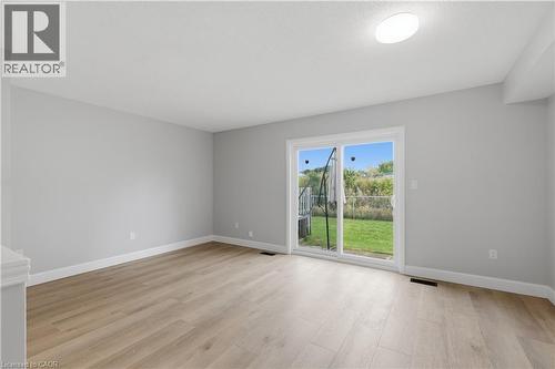 Light wood-finish flooring, white trim, and a sliding glass door to the backyard - 30 S Imperial Road Unit# 3, Guelph, ON 