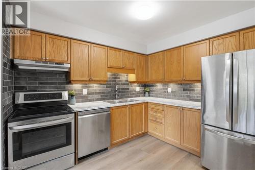 Stainless steel appliances, wood-finish cabinetry, subway tile backsplash, light wood-finish flooring, and under-cabinet lighting - 30 S Imperial Road Unit# 3, Guelph, ON 
