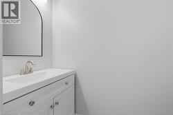 White vanity with brushed nickel hardware, integrated sink, and an arched mirror - 
