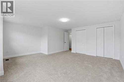Neutral wall paint with carpet flooring, flush mount ceiling light, and multiple bi-fold closet doors - 30 S Imperial Road Unit# 3, Guelph, ON 