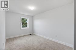 Neutral tone wall finish, white trim, light-colored carpeting, and a window with white casing - 