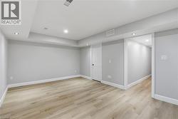 Recessed lighting, light wood-finish flooring, white trim, and a white interior door - 