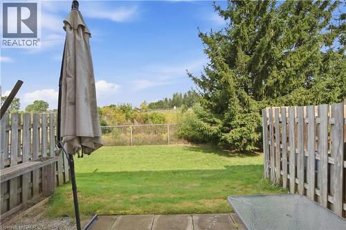 Expansive backyard featuring a lush lawn, mature evergreen trees, and a concrete patio - 30 S Imperial Road Unit# 3, Guelph, ON 