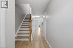 Hallway featuring wood-finish flooring and light gray painted walls - 
