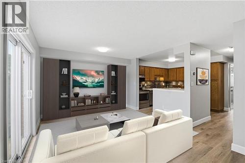 Open-concept living area featuring wood-finish flooring, built-in media storage, and a sliding glass door - 30 S Imperial Road Unit# 3, Guelph, ON 
