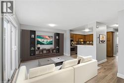 Open-concept living area featuring wood-finish flooring, built-in media storage, and a sliding glass door - 