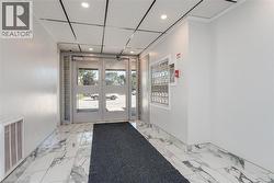 Front entry with glass double doors, recessed lighting, and marble-finish tile flooring - 