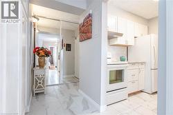 White kitchen cabinetry, full-size white appliances, tile backsplash, and light-toned countertops - 