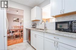 White shaker-style cabinetry with chrome hardware, light-toned granite countertops, and a subway tile backsplash - 