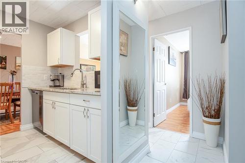 Kitchen featuring white cabinetry, a light-toned countertop, a tile backsplash, and stainless steel appliances - 71 Vanier Drive Unit# 310, Kitchener, ON 