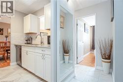 Kitchen featuring white cabinetry, a light-toned countertop, a tile backsplash, and stainless steel appliances - 