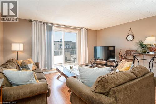 Sliding glass door to balcony, wood-finish flooring, neutral wall paint, and overhead lighting - 71 Vanier Drive Unit# 310, Kitchener, ON 
