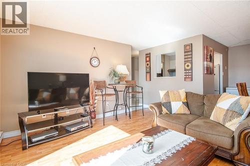 Wood-finish flooring, neutral wall tones, and a pass-through window define this living area - 71 Vanier Drive Unit# 310, Kitchener, ON 