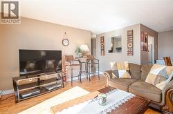 Wood-finish flooring, neutral wall tones, and a pass-through window define this living area - 