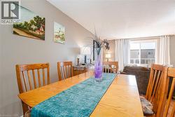 Open-concept dining area with wood-finish flooring, neutral wall tones, and a sliding glass door to an outdoor space - 