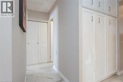 Hallway featuring white paneled bi-fold doors, built-in white cabinetry with decorative hardware, and large format tile flooring - 