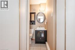 Bathroom featuring a vanity with a vessel sink, an oval mirror, and a wall-mounted light fixture - 