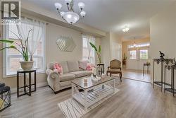 Wood-finish flooring, multiple large windows, and a decorative chandelier - 