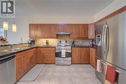 U-shaped kitchen with beautiful cabinetry, stainless steel appliances, dark granite countertops, and tiled flooring - 