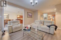 Open concept living space featuring wood-finish flooring, recessed lighting, and a chandelier - 