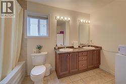 Dual vanity with integrated sinks, wood-finish cabinetry, and tiled flooring - 