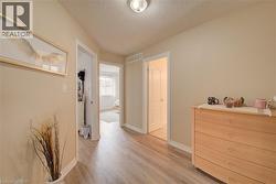 Wood-finish flooring throughout the hallway, neutral wall tones, and white trim - 