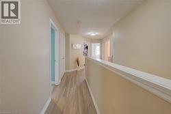 Hallway featuring wood-finish flooring, neutral wall paint, white trim, and recessed lighting - 