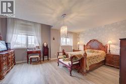 Wood-finish flooring throughout, a decorative accent wall, two windows with blinds, and a crystal chandelier - 