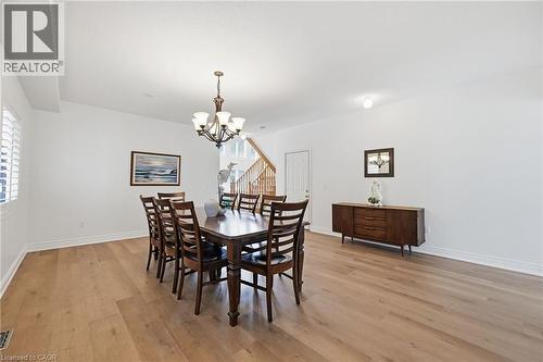 Spacious room featuring wood-finish flooring, white walls, and a multi-light chandelier - 3198 Tim Dobbie Drive, Burlington, ON 
