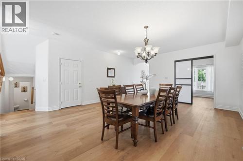Spacious room with wood-finish flooring, a tiered chandelier, and a sliding door with frosted panels - 3198 Tim Dobbie Drive, Burlington, ON 