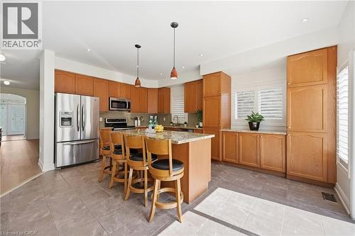 Kitchen featuring a center island with bar seating, light wood-finish cabinetry, stainless steel appliances, and a tiled floor - 3198 Tim Dobbie Drive, Burlington, ON 