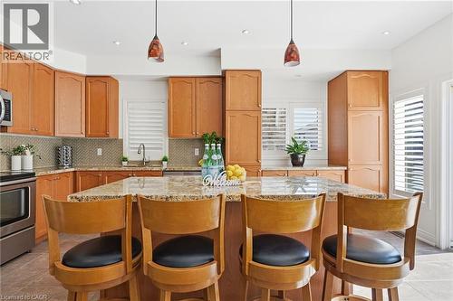 Kitchen featuring wood cabinetry, granite countertops, stainless steel appliances, and a central island with bar seating - 3198 Tim Dobbie Drive, Burlington, ON 