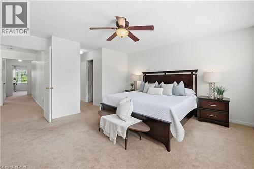 Carpeted bedroom featuring a ceiling fan with integrated lighting, a hallway entry, and an additional room visible through a doorway - 3198 Tim Dobbie Drive, Burlington, ON 