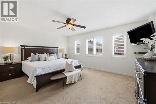 Spacious room featuring neutral carpeting, a ceiling fan, and multiple windows with plantation shutters - 3198 Tim Dobbie Drive, Burlington, ON 