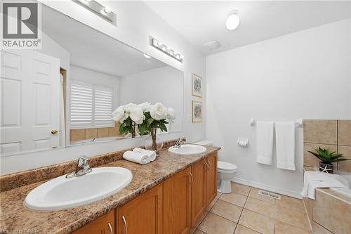 Dual vanity with integrated sinks, wood-finish cabinetry, and a full-width mirror - 3198 Tim Dobbie Drive, Burlington, ON 