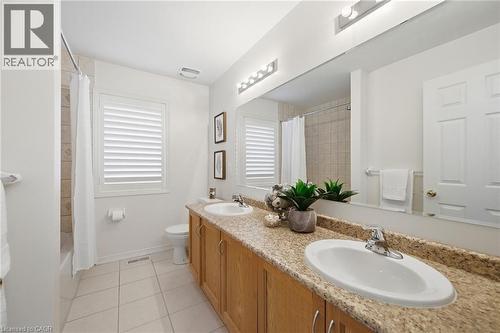 Spa-inspired master bathroom showcasing a dual-sink vanity with warm wood cabinetry, granite countertops, and polished chrome fixtures - 3198 Tim Dobbie Drive, Burlington, ON 