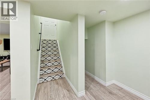 Wood-finish flooring throughout, complemented by a staircase featuring a decorative patterned riser and a black-finish handrail - 3198 Tim Dobbie Drive, Burlington, ON 