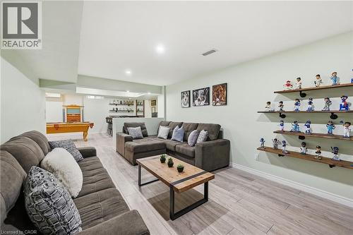 Spacious recreational room featuring wood-finish flooring, recessed lighting, built-in shelving, and a wet bar with open shelving - 3198 Tim Dobbie Drive, Burlington, ON 