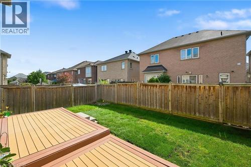 Tiered wood-finish deck, surrounded by a wood privacy fence, featuring a grassy lawn - 3198 Tim Dobbie Drive, Burlington, ON 