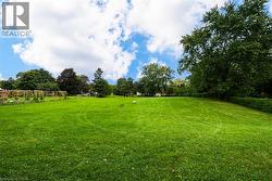 Expansive green lawn with mature trees and a structured garden area - 