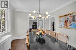 Wood-finish flooring, crown molding, modern sputnik chandelier, white window trim, and baseboard heating unit - 