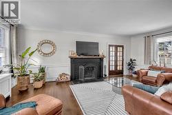 Hardwood flooring throughout, a decorative fireplace with a dark mantel, white wainscoting, and crown molding - 