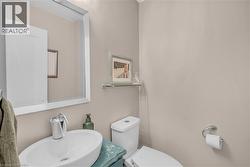 White rectangular framed mirror, oval vessel sink, chrome single-handle faucet, glass wall shelf, and a white toilet - 