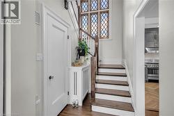 Rich wood-finish staircase with white risers and balustrade, complemented by a decorative leaded glass window - 